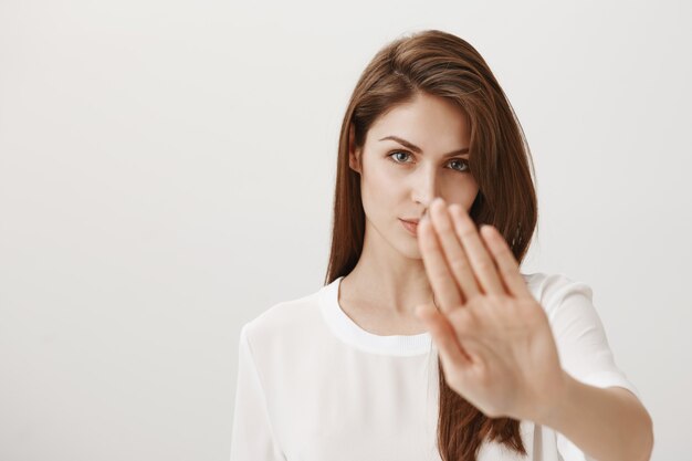 Ernstig uitziende vrouw steekt haar hand uit om stopgebaar te tonen, keurt actie af