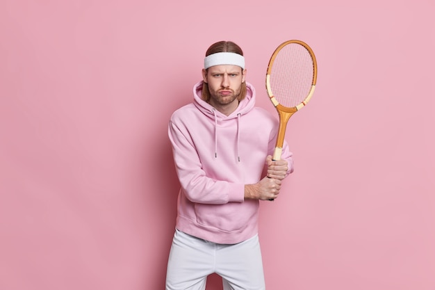 Ernstige actieve sportman staat met tennisracket speelt favoriete spel gaat in voor sport voor gezondheid