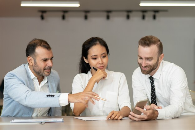 Ernstige bedrijfsmensen die en smartphone werken bij bureau gebruiken