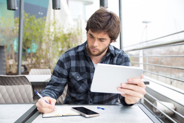 Ernstige fronsende student die aan onderzoekdocument werkt