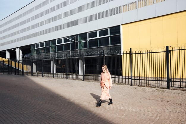 Ernstige jonge blonde dame die in openlucht loopt. Opzij kijken.