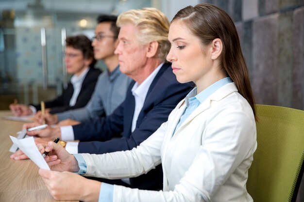 Ernstige jonge zakenvrouw zittend op de conferentie