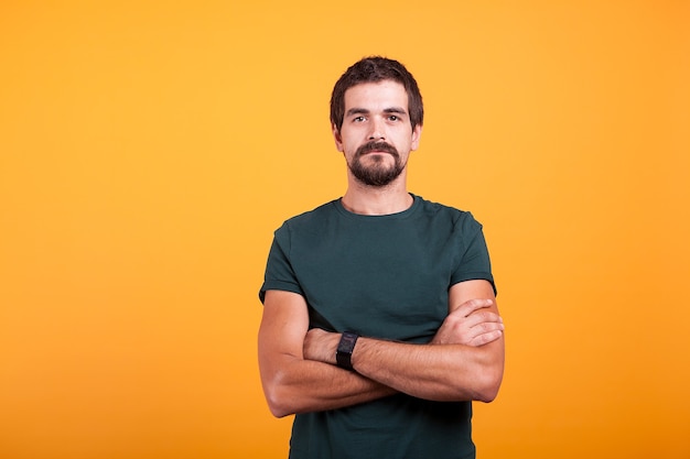 Ernstige man geïsoleerd op een oranje achtergrond. Zelfverzekerde persoon die in de camera kijkt