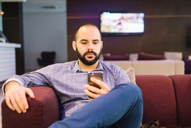 Ernstige man met telefoon thuis