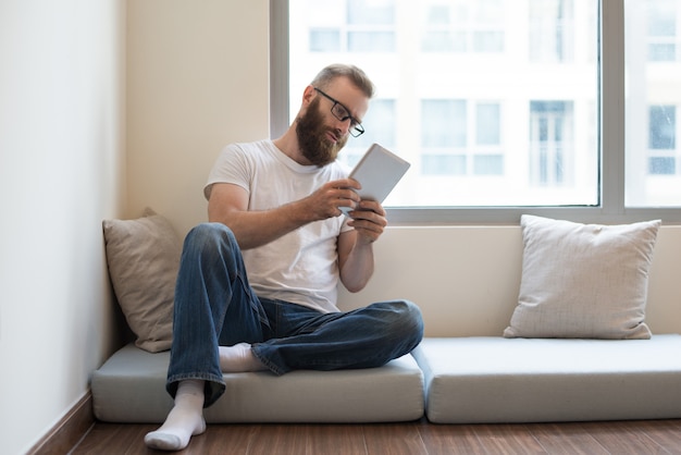 Ernstige peinzende jonge man in glazen die online artikel lezen