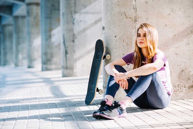 Ernstige sportmeisje zitten met een skateboard