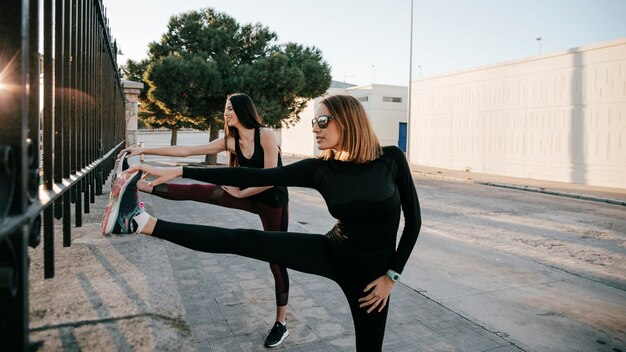 Gratis foto ernstige sportvrouwen die spieren op straat uitrekken