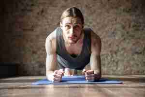 Gratis foto ernstige sterke sportman in de sportschool maken yoga sport oefeningen.