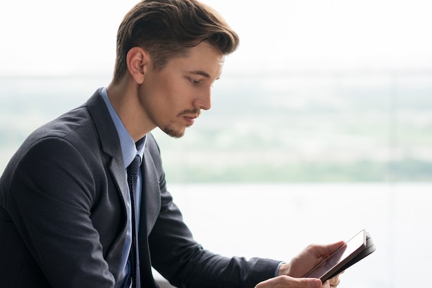 Ernstige volwassen zakenman zitten en met behulp van de Tablet