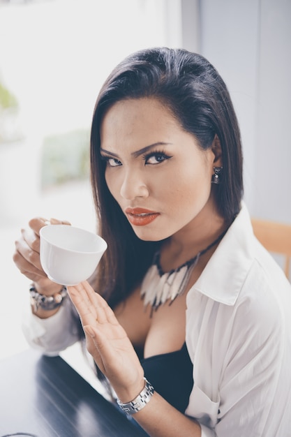 Ernstige vrouw drinken van een kopje koffie