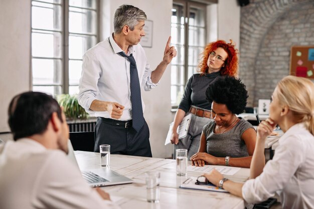 Ernstige zakenman legt iets uit aan zijn collega's tijdens een vergadering op kantoor