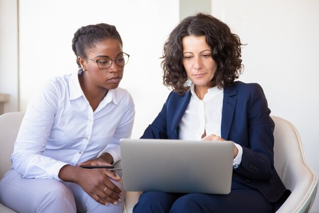 Ernstige zakenvrouwen kijken naar presentatie samen