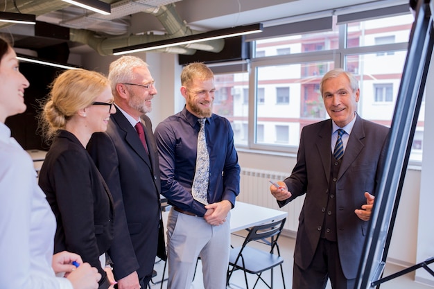 Gratis foto ervaren glimlachende zakenman die presentatie geeft aan uitvoerend team