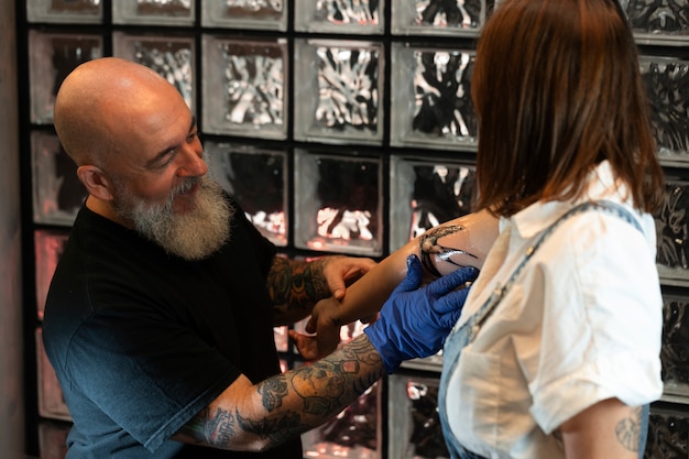 Ervaren tatoeëerder bezig met tatoeage van klanten