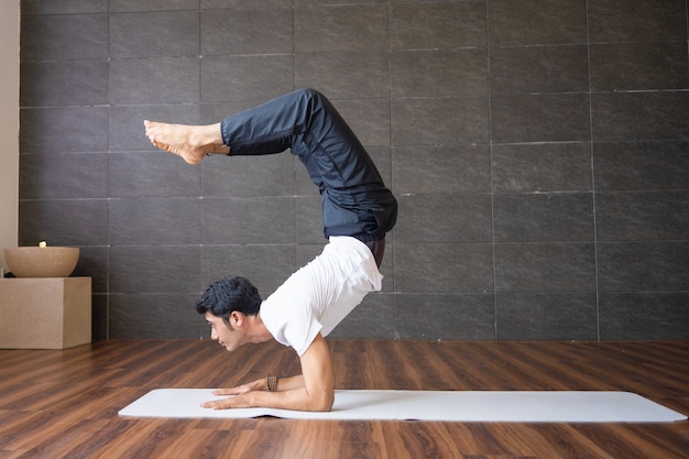 Ervaren yogi die scorpion yoga doet in de sportschool