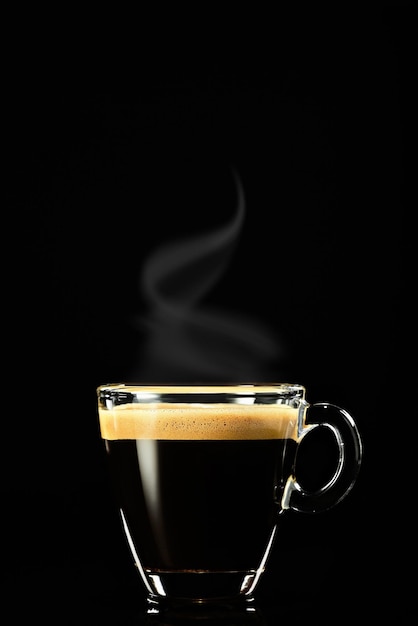 Espresso op een donkere achtergrond, de stoom stijgt boven de koffie uit. Koffie voor het ontbijt in een Italiaanse caféwinkel, verticaal schot, selectieve focus