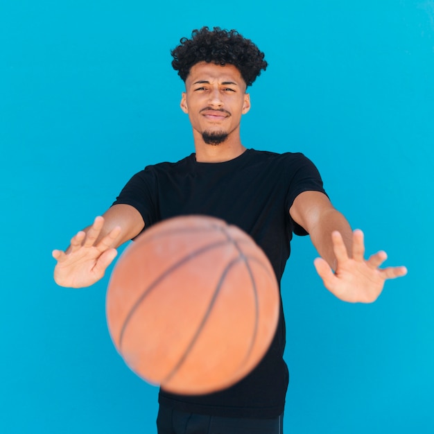 Etnische jonge man basketbal gooien naar de camera