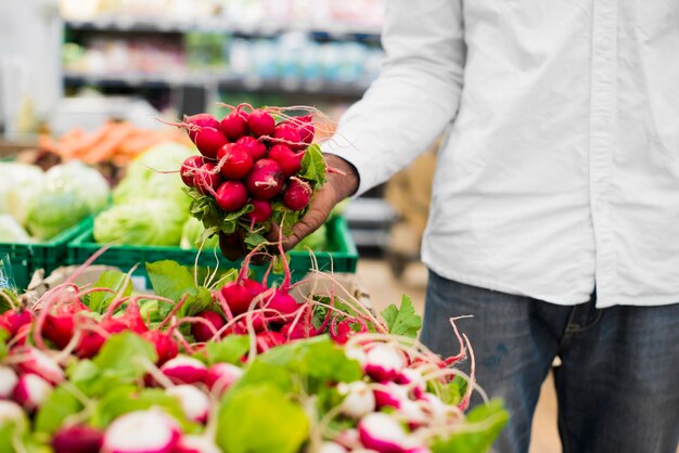 Etnische man plukken radijs in supermarkt