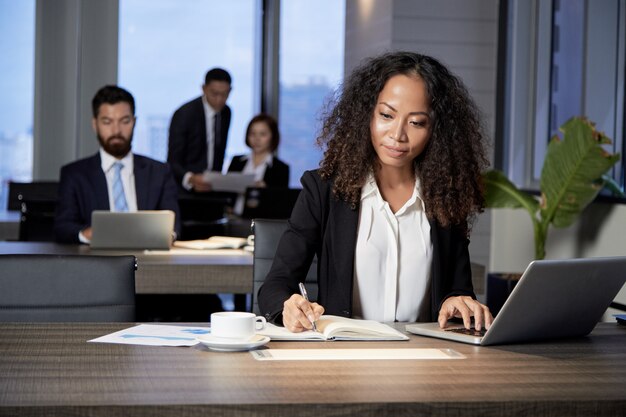 Etnische onderneemster die in modern bureau werkt