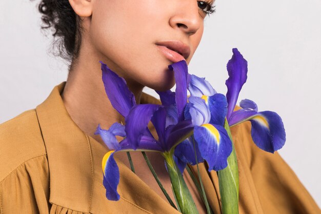 Gratis foto etnische vrouw met bloemen dichtbij gezicht
