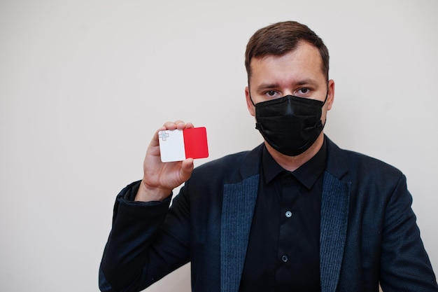 Europese man draagt zwart formeel en beschermt gezichtsmasker houdt malta-vlagkaart geïsoleerd op witte achtergrond europa coronavirus covid-landconcept