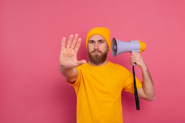 Gratis foto europese man houdt megafoon stopbord op roze achtergrond weergeven
