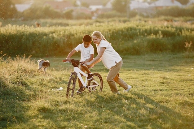 Europese moeder en Afrikaanse zoon. Familie in een zomerpark. Kid met fiets.