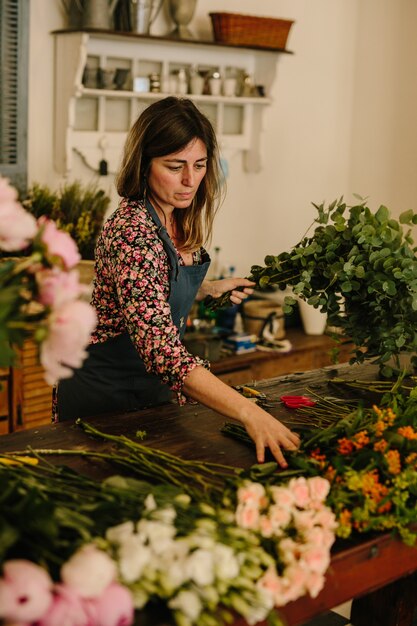 Europese vrouwelijke bloemist met een groen schort die bloemstukken maakt in een bloemsierkunststudio