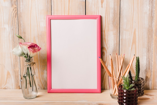 Eustoma vaas; cactus plant en een glas kleurpotloden en lege witte frame