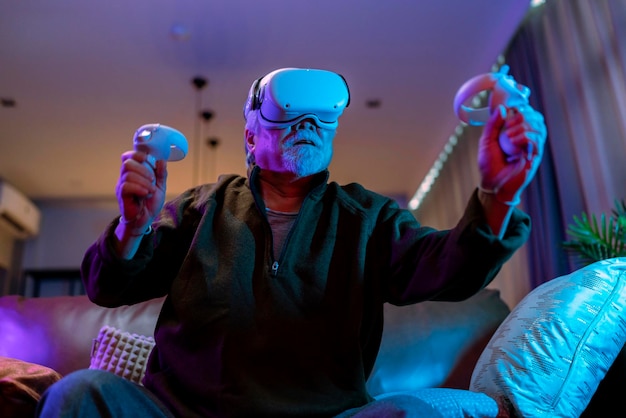 Exicet aziatische senior oude man witte baard geniet van virtuele augmented reality metaverse esport online digitaal wereldspel in de woonkamer thuiscasial relax oude man speel digitaal vrijetijdsspel thuis