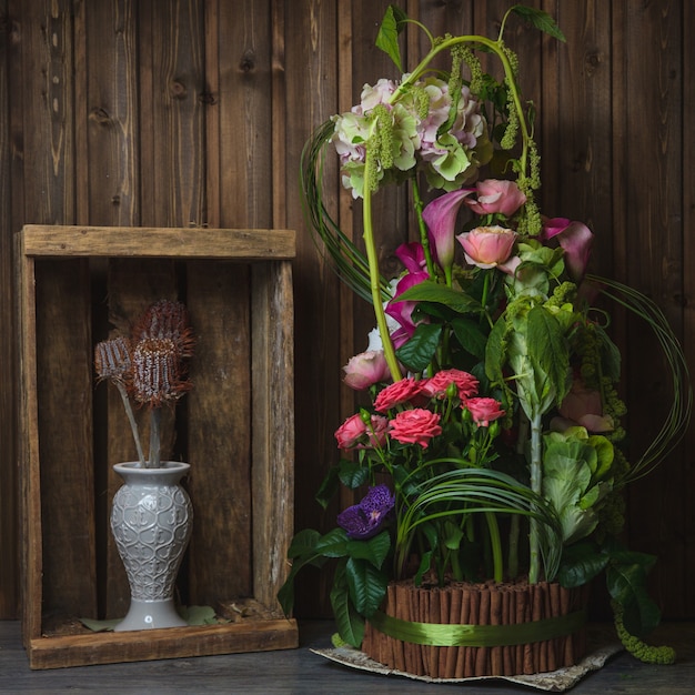 Exotisch bloemboeket binnen houten mand die met groen lint wordt verpakt.