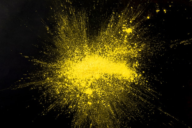 Explosie geel gekleurd poeder op zwart oppervlak
