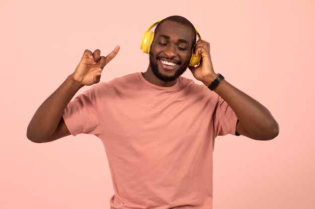 Gratis foto expressieve afro-amerikaanse man die naar muziek luistert op een koptelefoon