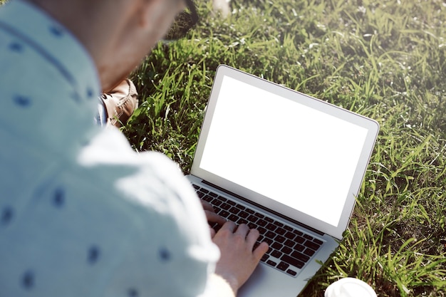 Expressieve man is in het park met zijn laptop