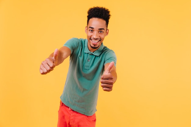 Gratis foto extatische afrikaanse man koelen. portret van zelfverzekerd zwart mannelijk model in groene t-shirt.