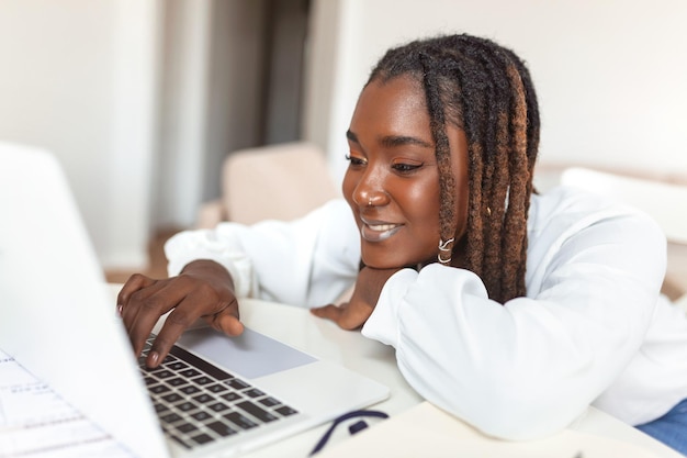 Externe baantechnologie en mensenconcept jonge Afrikaanse zakenvrouw met laptopcomputer en papieren die thuis werken tijdens de Covid19-gezondheidscrisis