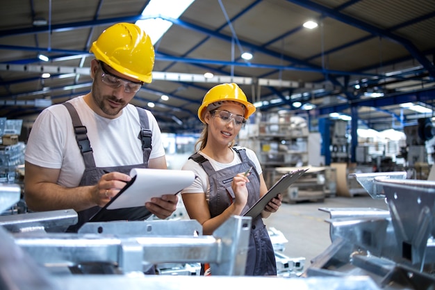 Gratis foto fabrieksarbeiders die de kwaliteit van producten in grote industriële hal controleren