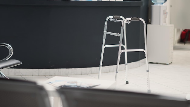 Faciliteit wachtkamer met loopframe in lobby, lege receptiebalie met controleformulieren en zitplaatsen in wachtruimte. medisch centrum met hulp bij chronische handicap, gezondheidszorg.