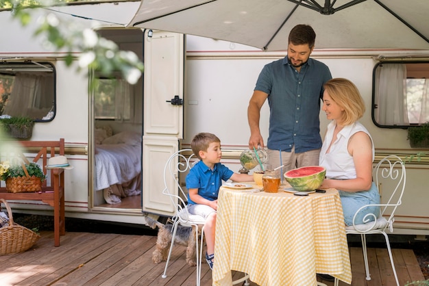 Gratis foto familie die de lunch naast een caravan neemt