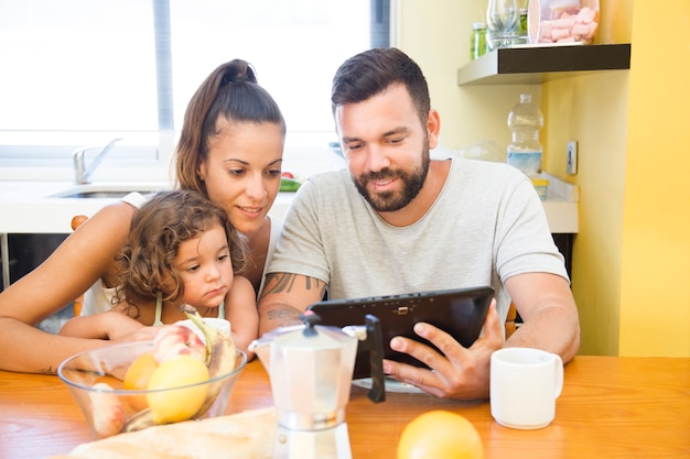 Familie die het digitale tabletscherm tijdens ontbijt bekijkt