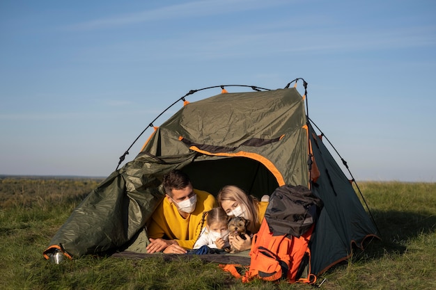 Familie die maskers draagt en in tent met hun hond zit