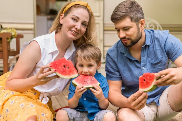 Familie die samen watermeloen naast een caravan eet