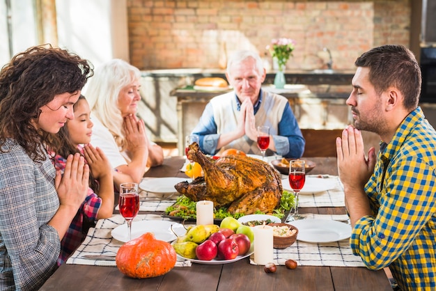 Familie die vóór maaltijd bidden