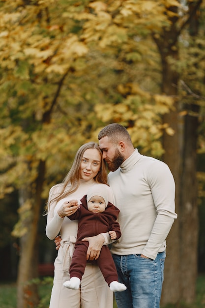 Familie in een herfstpark. Man in een bruine trui. Leuk meisje met ouders.