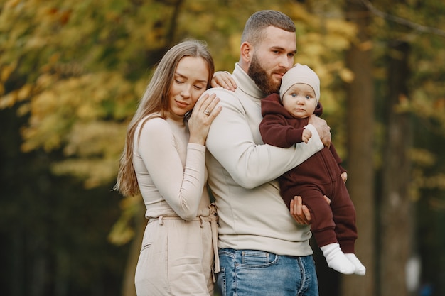 Familie in een herfstpark. Man in een bruine trui. Leuk meisje met ouders.