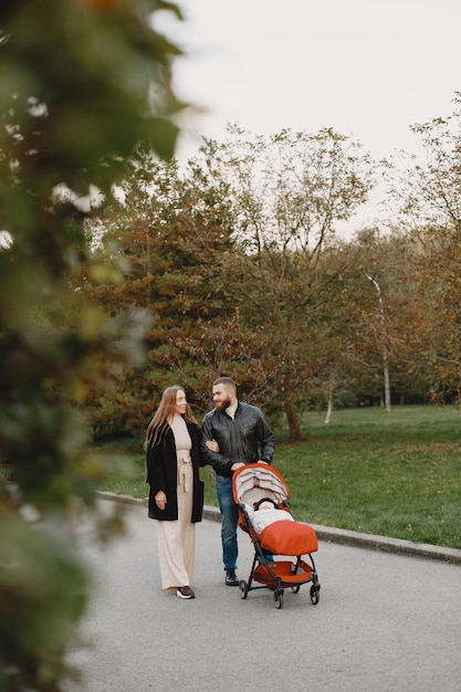 Familie in een herfstpark. Man in een zwart jasje. Leuk meisje met ouders.