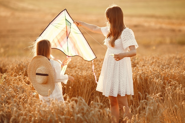 Familie in een tarweveld. Vrouw in een witte jurk. Klein kind met vlieger.