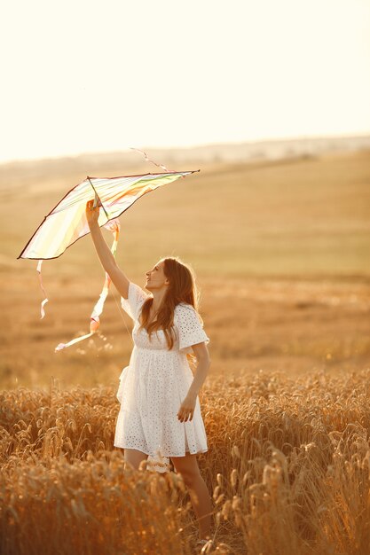 Familie in een tarweveld. Vrouw in een witte jurk. Klein kind met vlieger.