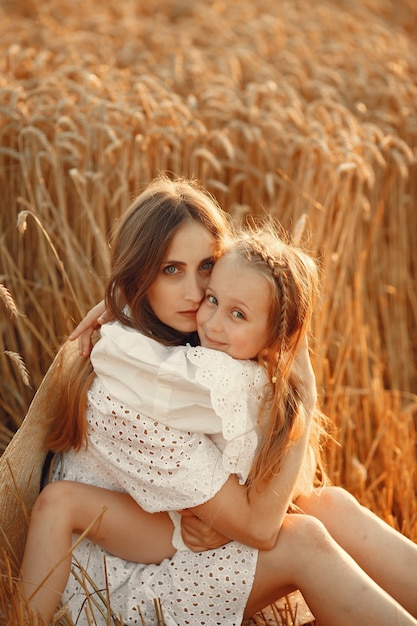 Gratis foto familie in een tarweveld. vrouw in een witte jurk. meisje met strohoed.