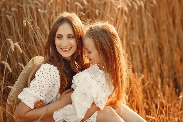 Familie in een tarweveld. Vrouw in een witte jurk. Meisje met strohoed.